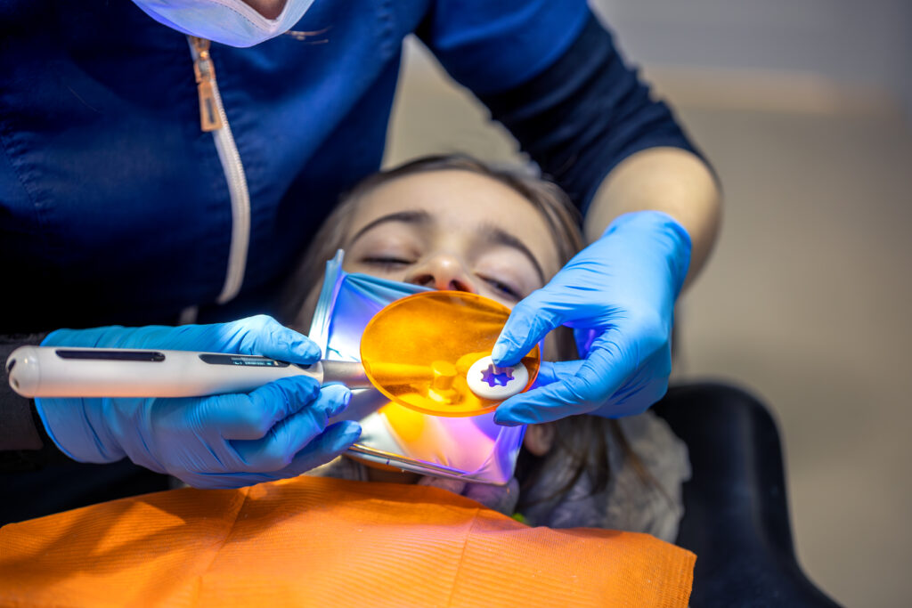 Dental fillings. Dental fillings with ultraviolet light. Female dentist treating a girl's tooth.